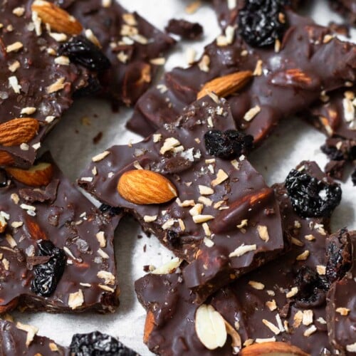 Sheet pan of pieces of chocolate bark with almonds, dried cherries, and shredded coconut sprinkled with flaky sea salt.