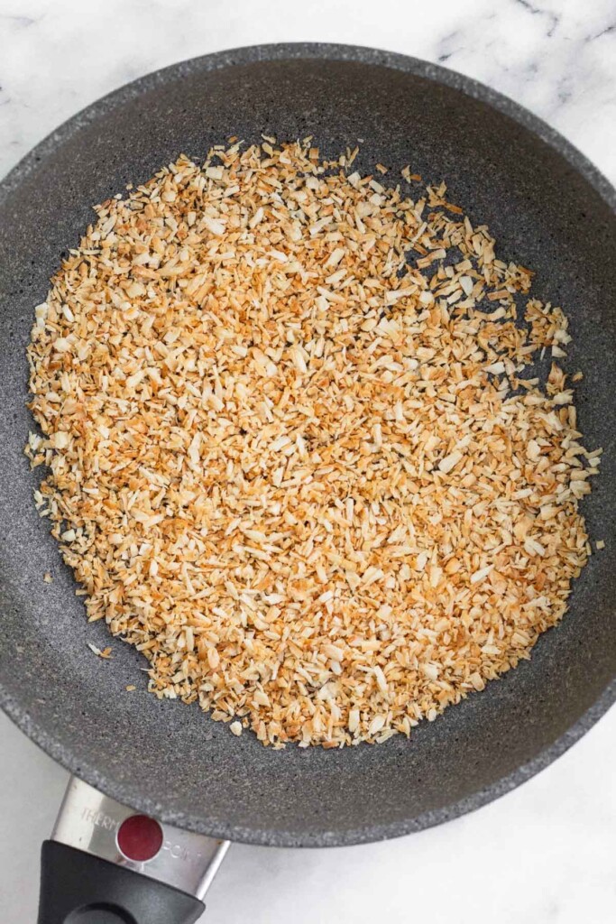 Small saute pan with toasted shredded coconut in it.