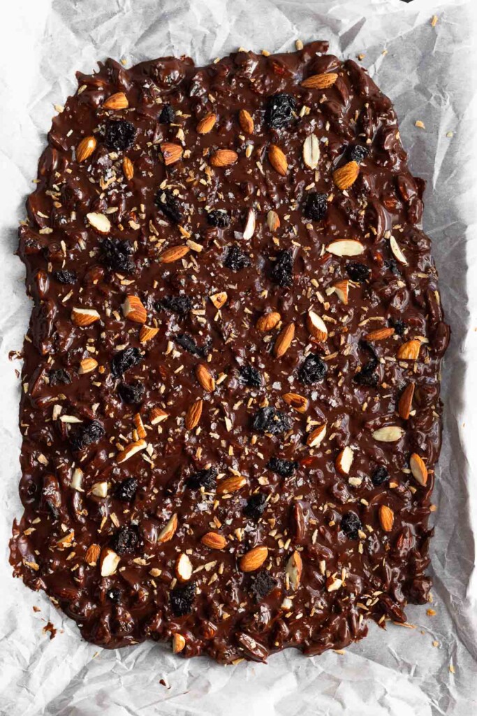 Chocolate bark spread on a baking sheet before it is chilled.