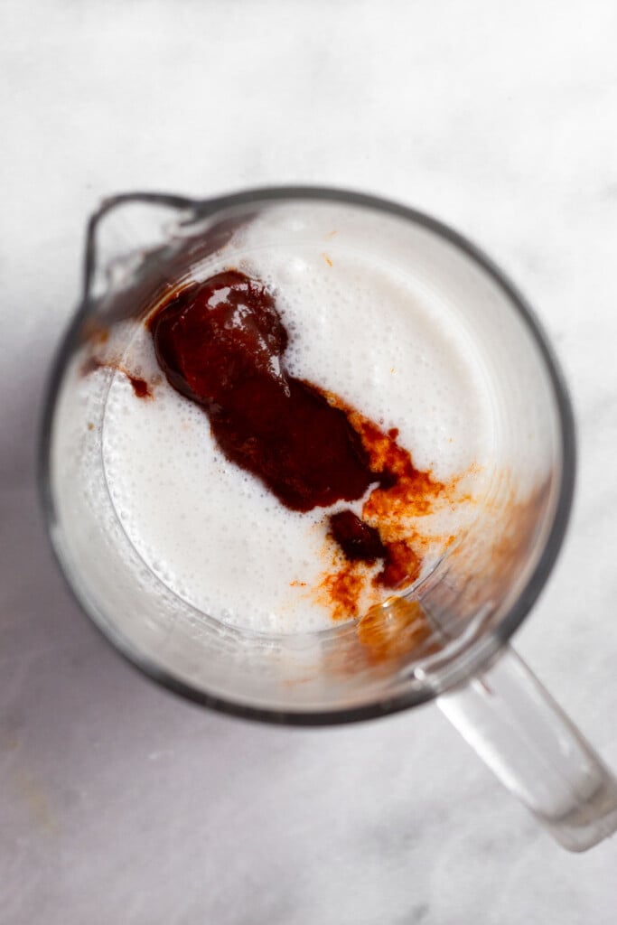 Measuring cup with coconut milk and chipotles in adobo sauce in it.