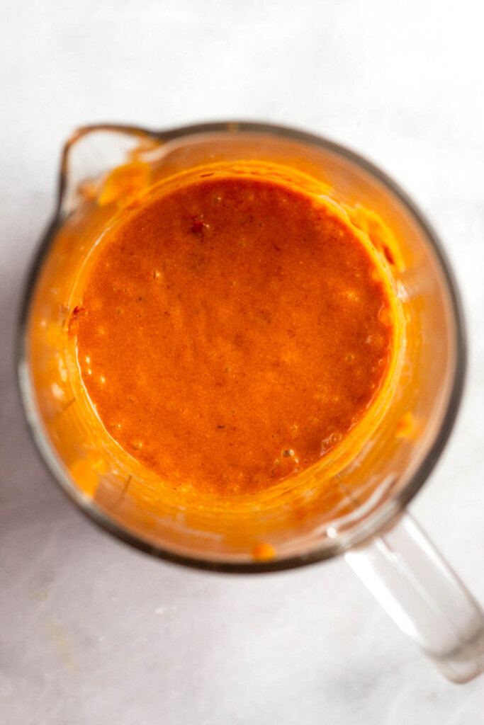 A creamy mixture of coconut milk and chipotles in adobo sauce in a glass measuring cup.