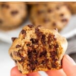 A hand holding a cottage cheese muffin with a bite taken out of it. In the background is a plate of more muffins.