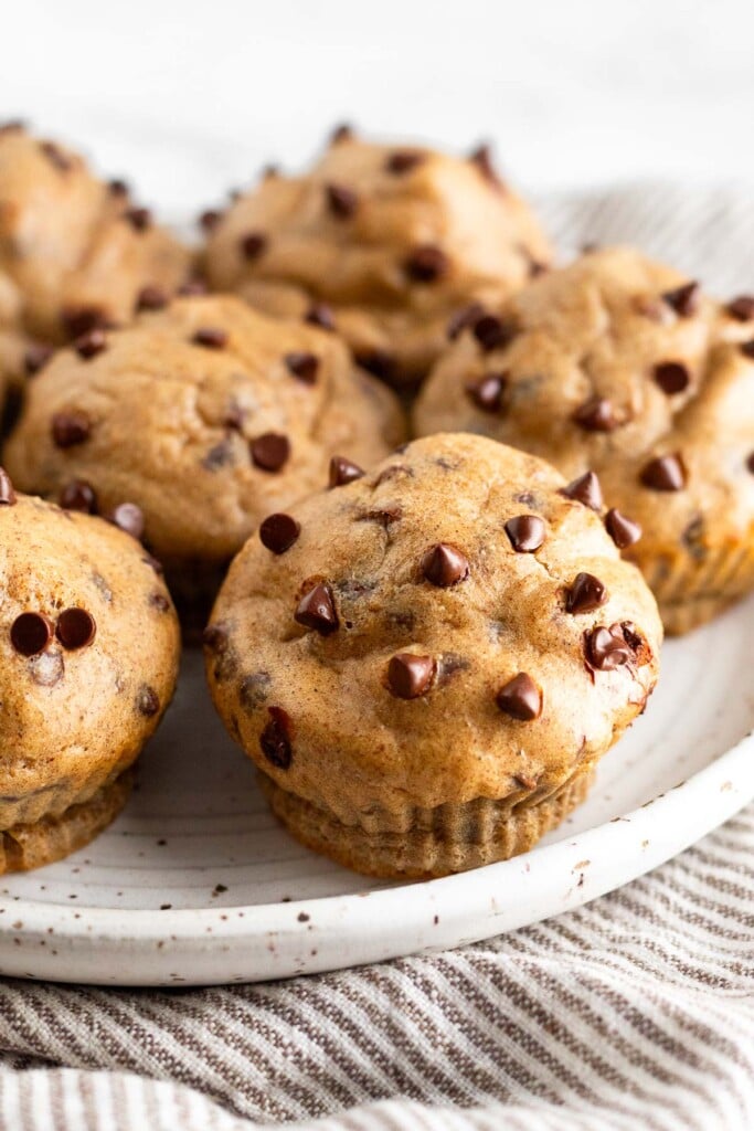 Healthy cottage cheese muffins with chocolate chips on a white plate on top of a striped towel.