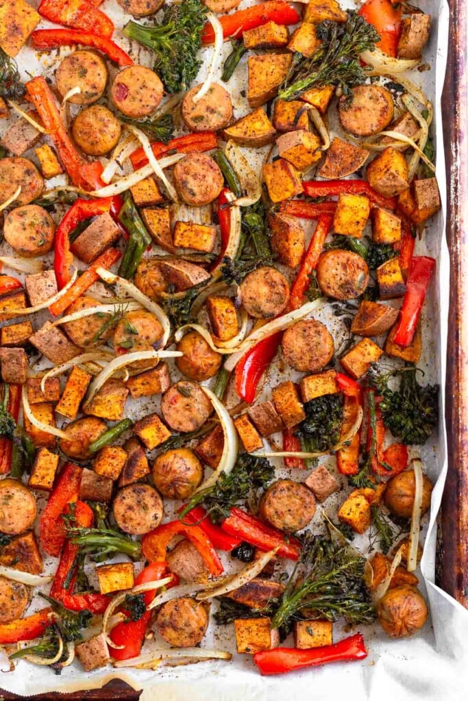 Sausage sheet pan dinner with roasted sweet potatoes, onions, peppers, and broccoli.