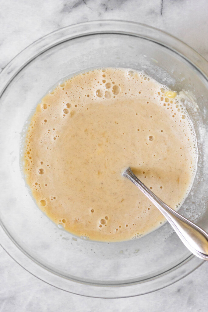 Glass bowl with a wet batter and a fork in it.