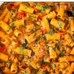 Cottage cheese pasta with ground turkey and veggies in a large skillet garnished with basil and parmesan cheese. The skillet is on top of a striped towel.