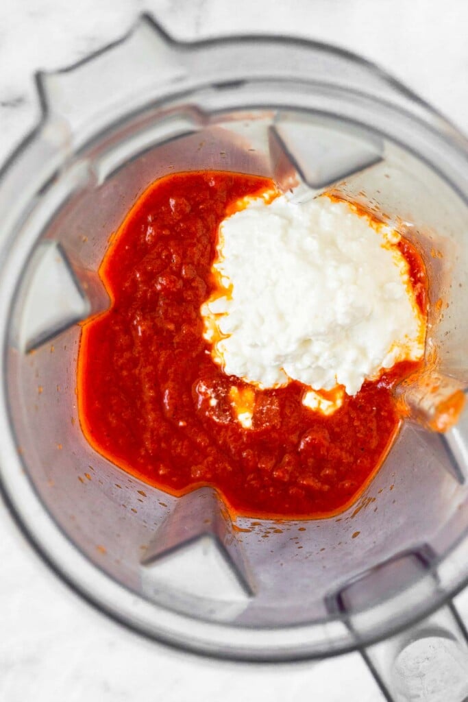 Blender with marinara sauce and cottage in it.