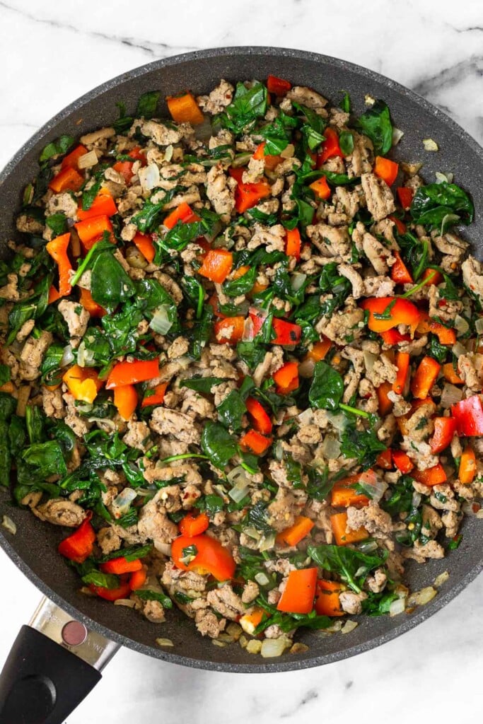 Large skillet filled with a mix of sautéed veggies and ground turkey.