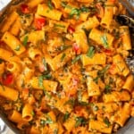 Cottage cheese pasta with ground turkey and veggies in a large skillet garnished with basil and parmesan cheese. The skillet is on top of a striped towel.