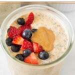 A jar of protein overnight oats topped with fresh diced strawberries, blueberries, and peanut butter.