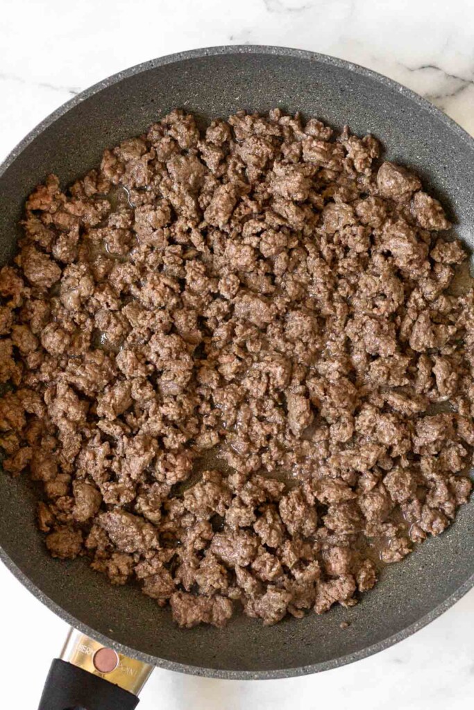 Large skillet filled with sautéed ground beef.