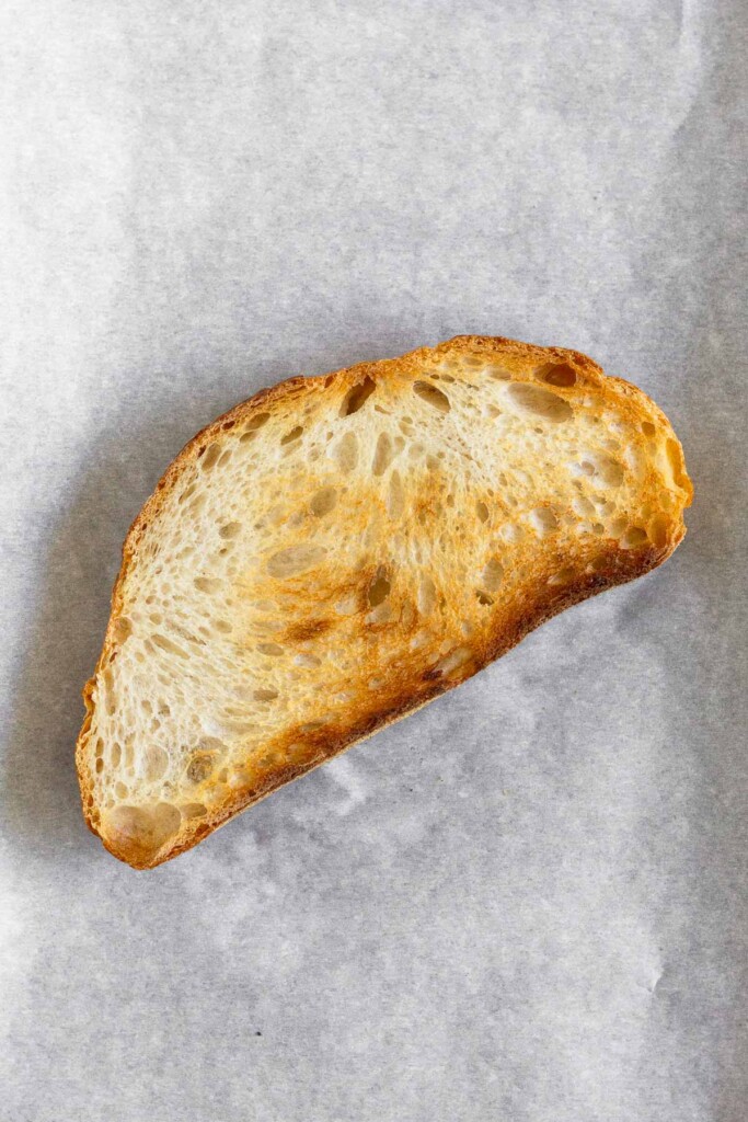 A piece of toasted sourdough on a piece of parchment paper.
