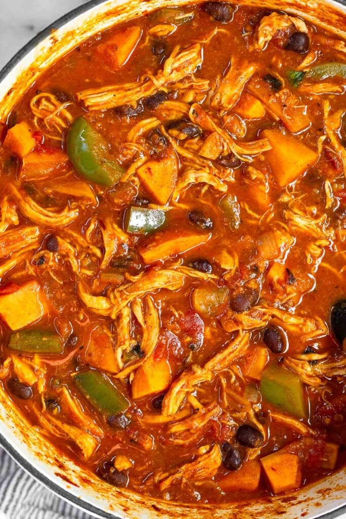 Overhead shot of soup with chicken, sweet potatoes, black beans, and veggies in a large pot.