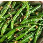 Sesame green beans with garlic in a large white bowl.