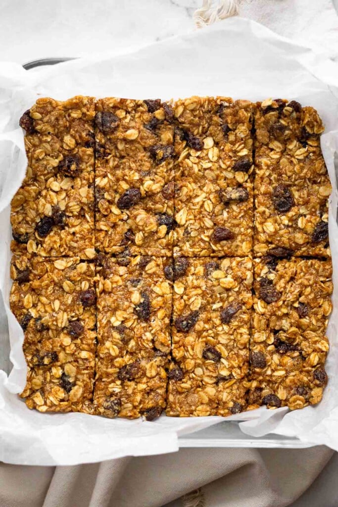 Glass baking dish lined with parchment paper filled with oatmeal protein bars cut into 8 equal bars.