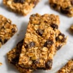 Two oatmeal raisin bars stacked on top of each other with more bars surrounding them.