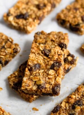 Two oatmeal raisin bars stacked on top of each other with more bars surrounding them.