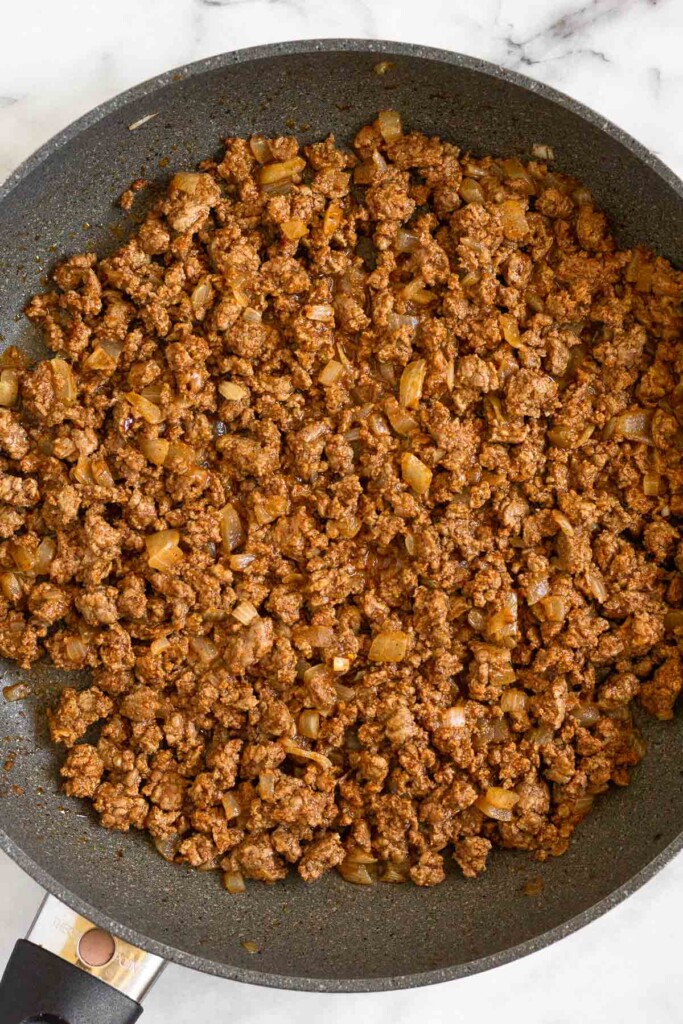 Large skillet filled with sautéed ground beef.