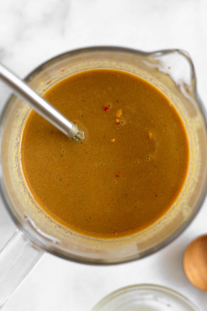 Cold sesame noodle sauce in a measuring cup with a whisk in it.