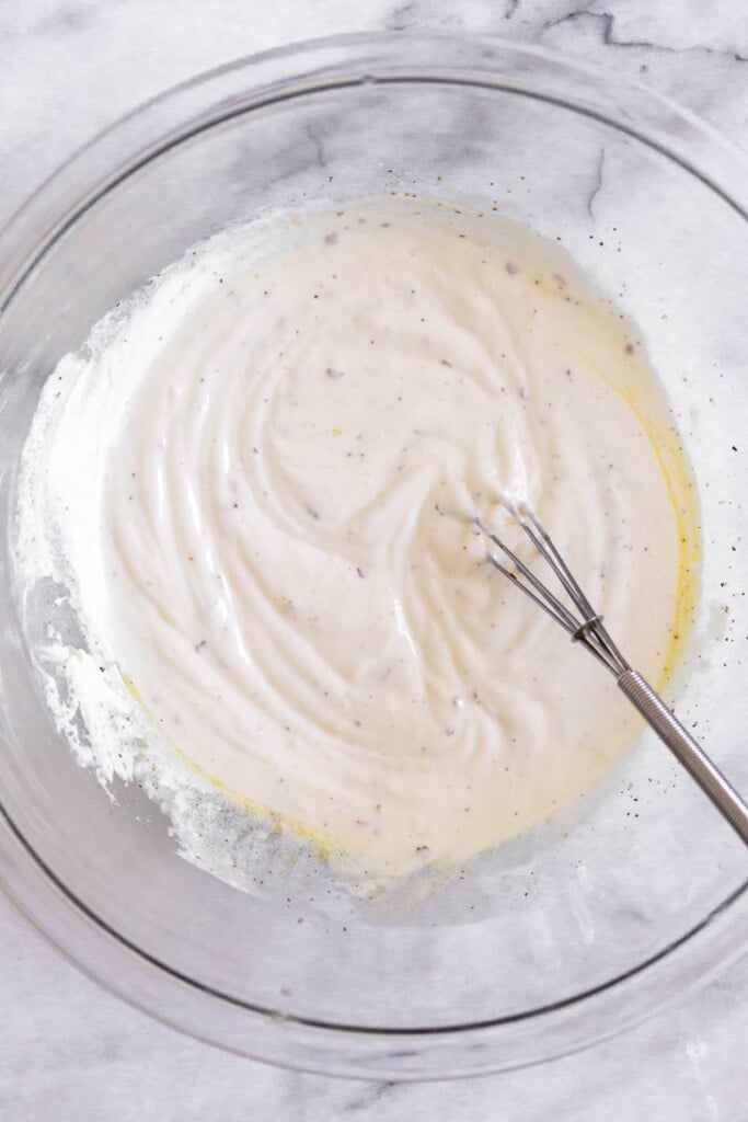 A large bowl with a greek yogurt mixture and a small whisk in it.