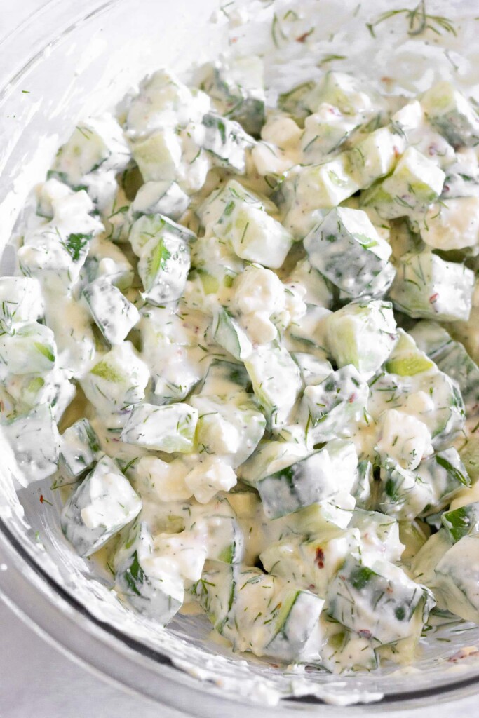 Greek yogurt cucumber salad with dill and feta in a glass bowl.
