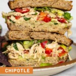 A chipotle chicken salad sandwich with lettuce and avocado stacked on top of each other on a plate.