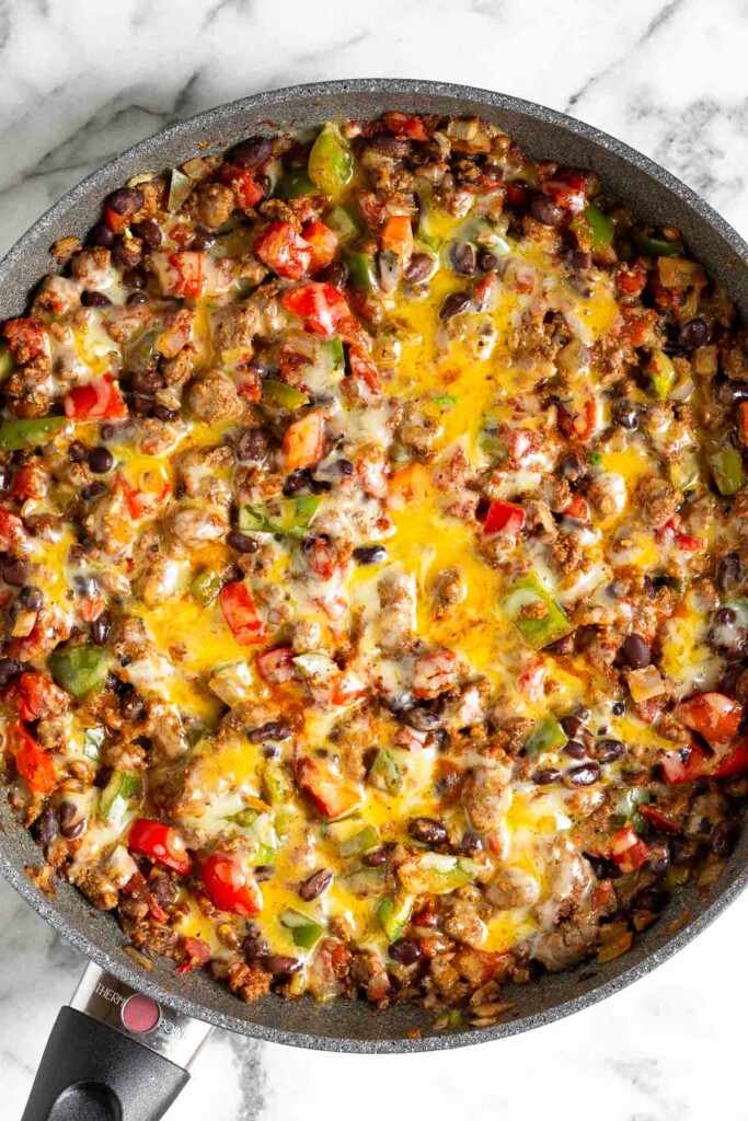 Beef taco skillet with black beans and vegges covered with melted cheese in a large sauté pan.
