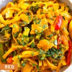 A close up of curry noodles with chicken and veggies in a white bowl topped with cilantro.