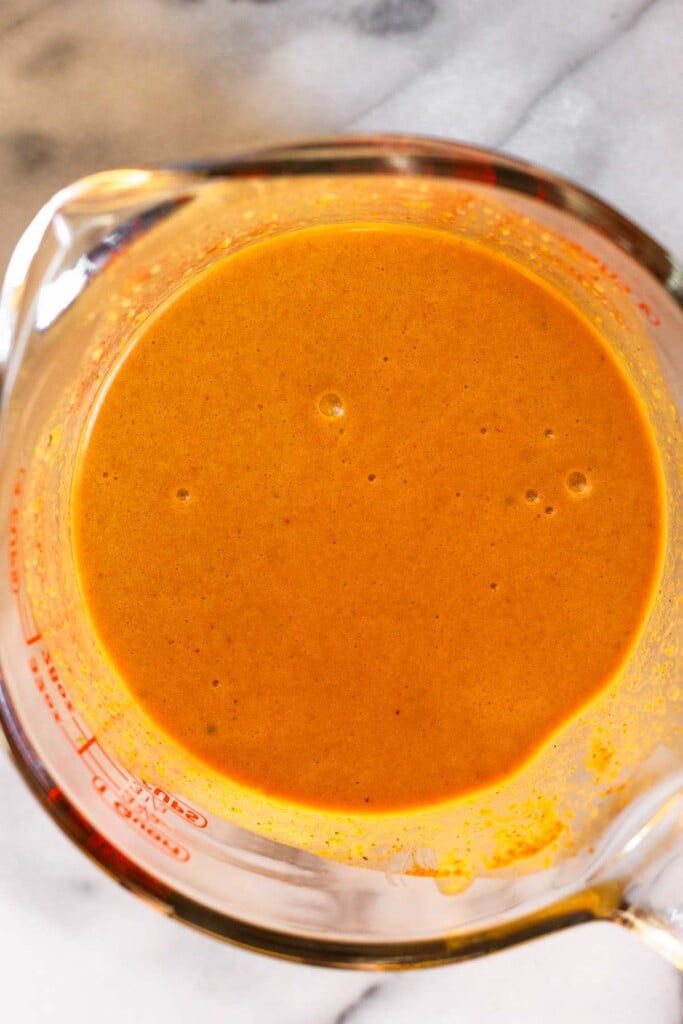 Large measuring up with red curry sauce in it.