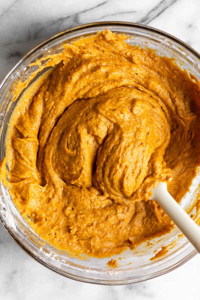 Overhead shot of a glass bowl filled with a thick batter with a spatula in it.