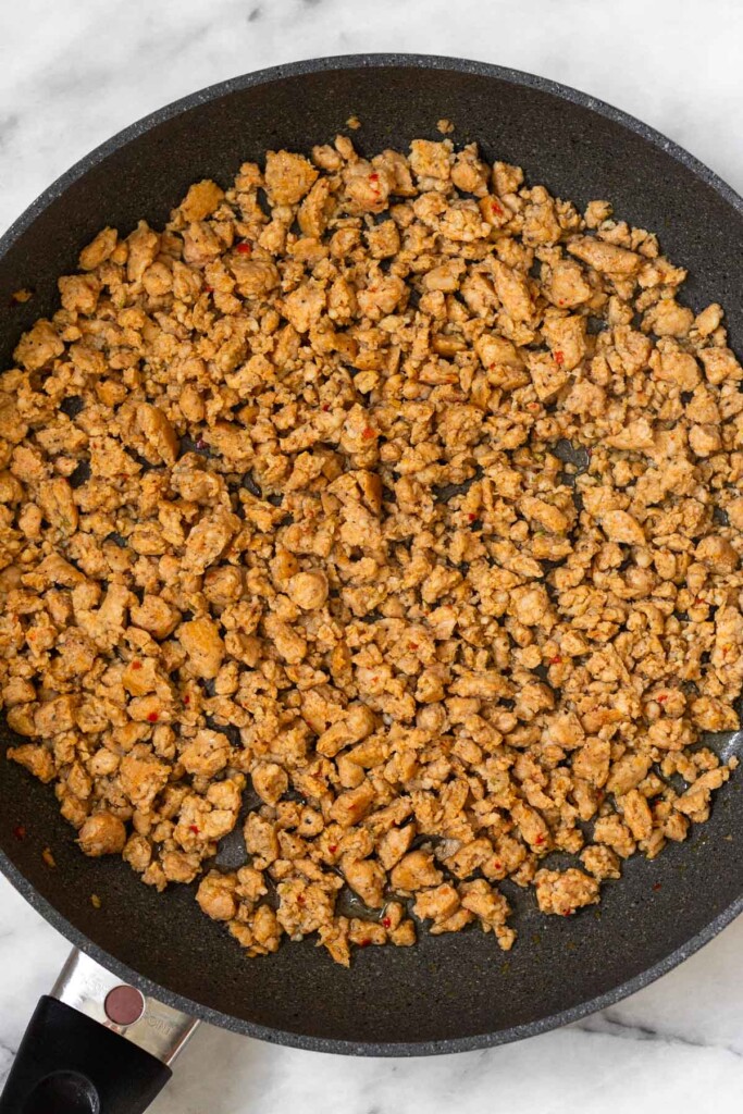 Large skillet filled with sautéed ground sausage.