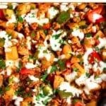 Sausage peppers and potatoes skillet topped with melted cheese and fresh parsley.