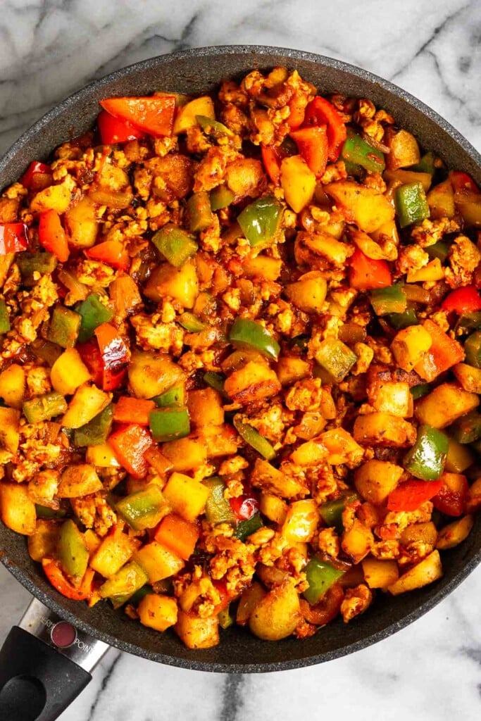 A mixture of ground meat, potatoes, peppers, and onions in marinara sauce in a large skillet.