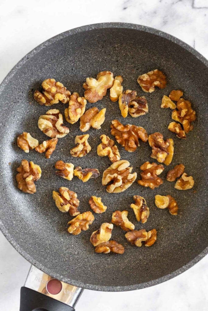 Small skillet with toasted walnuts in it.
