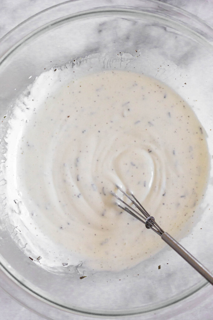 A large bowl with a greek yogurt mixture and a small whisk in it.