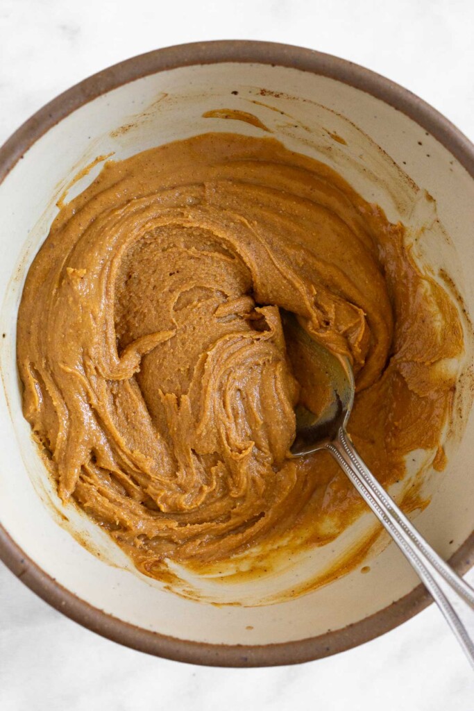 Peanut butter mixture in a white bowl with a spoon in it.