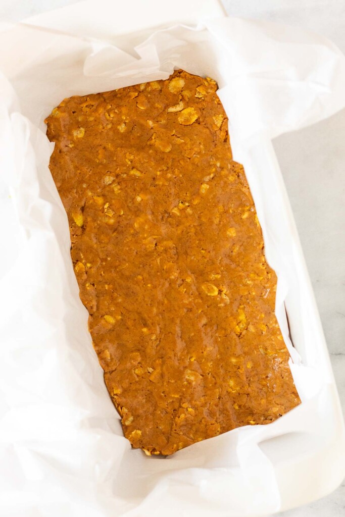 Dough pressed into a bread pan lined with parchment paper.