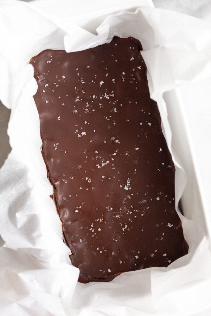 Bread pans filled with bars topped with chocolate and flaky sea salt before they are cut.
