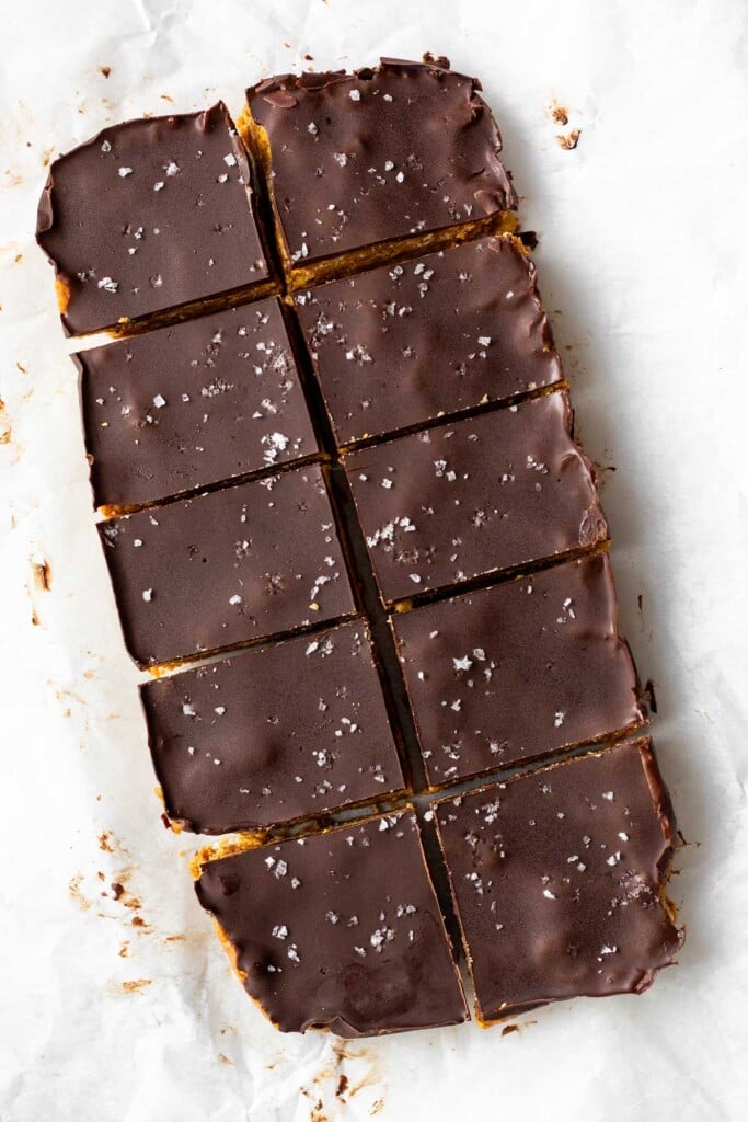 Peanut butter chocolate crunch bars cut into 10-equal size pieces on a piece of parchment paper. They are topped with flaky salt.