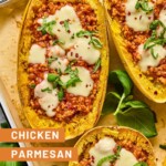 Chicken parmesan spaghetti squash boats on parchment paper lined baking sheet. Around the baking sheet is more fresh basil.