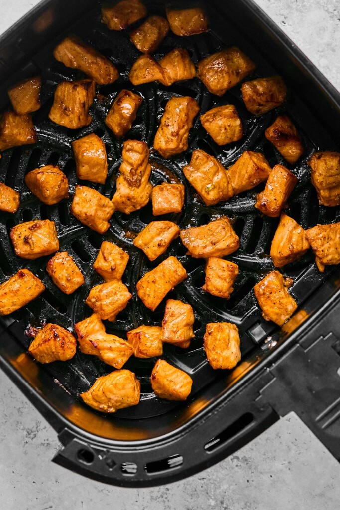Cooked salmon cubes in an air fryer basket.