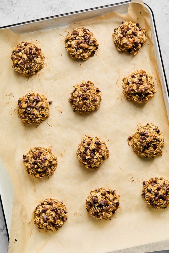 Healthy banana oatmeal cookies with chocolate chips on a baking sheet lined with parchment paper.