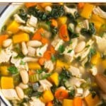 High protein soup with turkey, veggies, beans and butternut squash topped with fresh herbs in a large pot.
