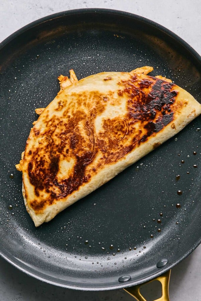 Chicken quesadilla cooking in a large skillet.