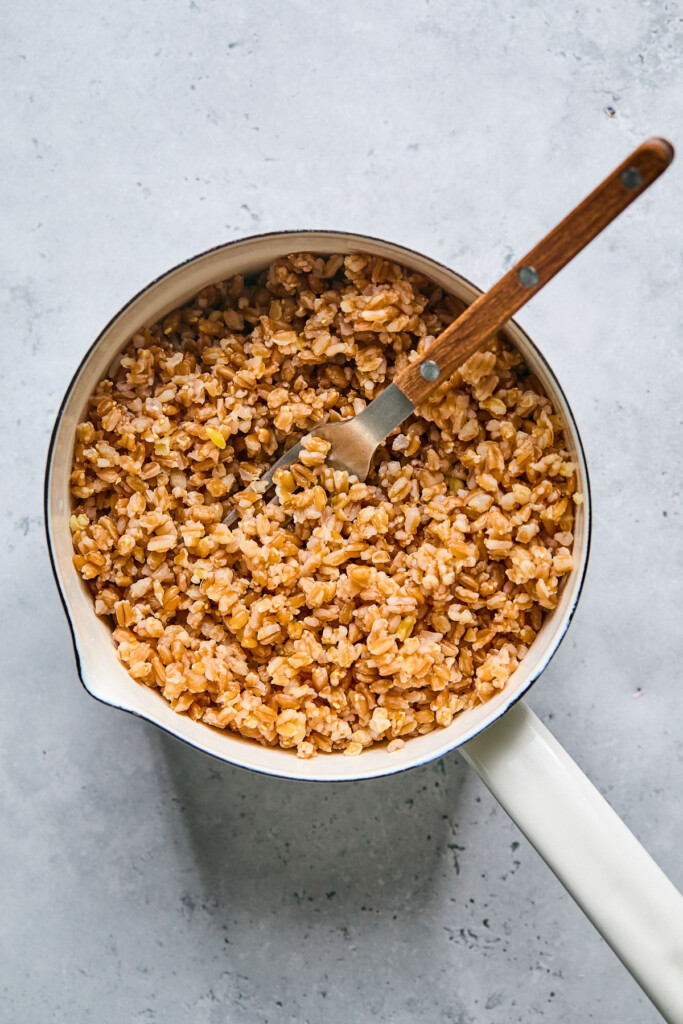 A pot filled with cooked farro with a fork in it.
