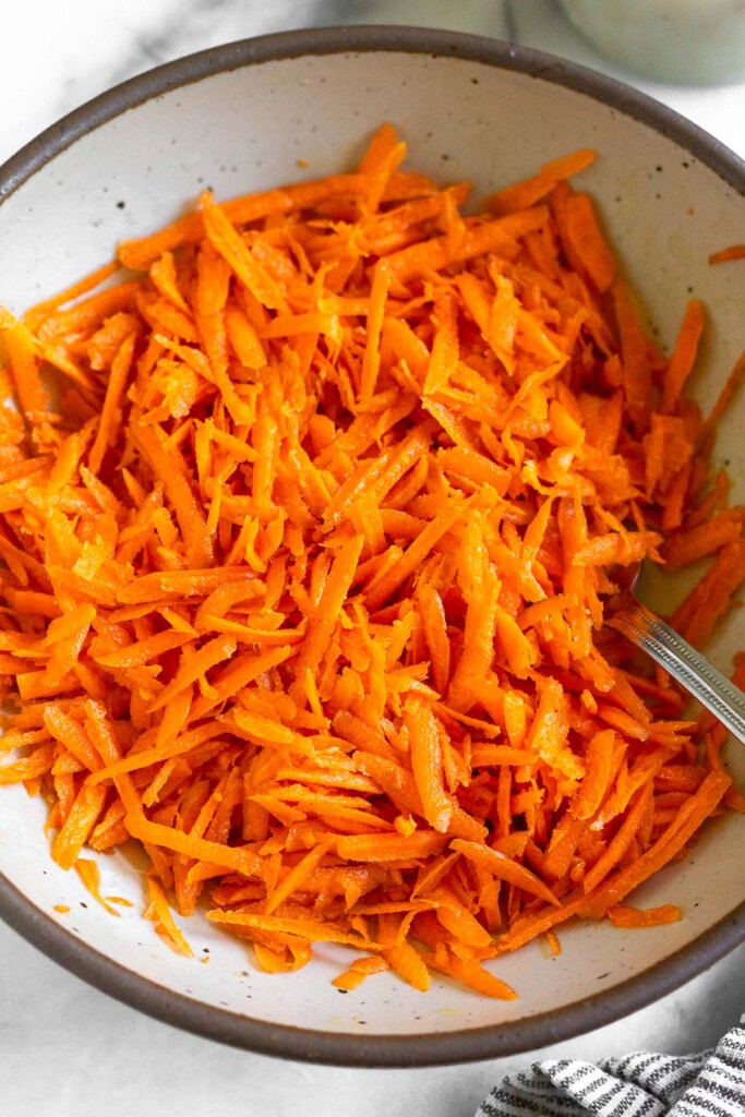 Ray peat carrot salad in a white bowl with a fork in it.
