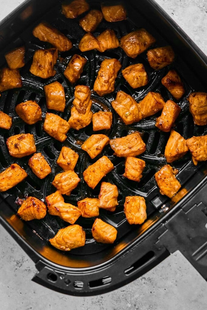 Cooked salmon cubes in an air fryer basket.