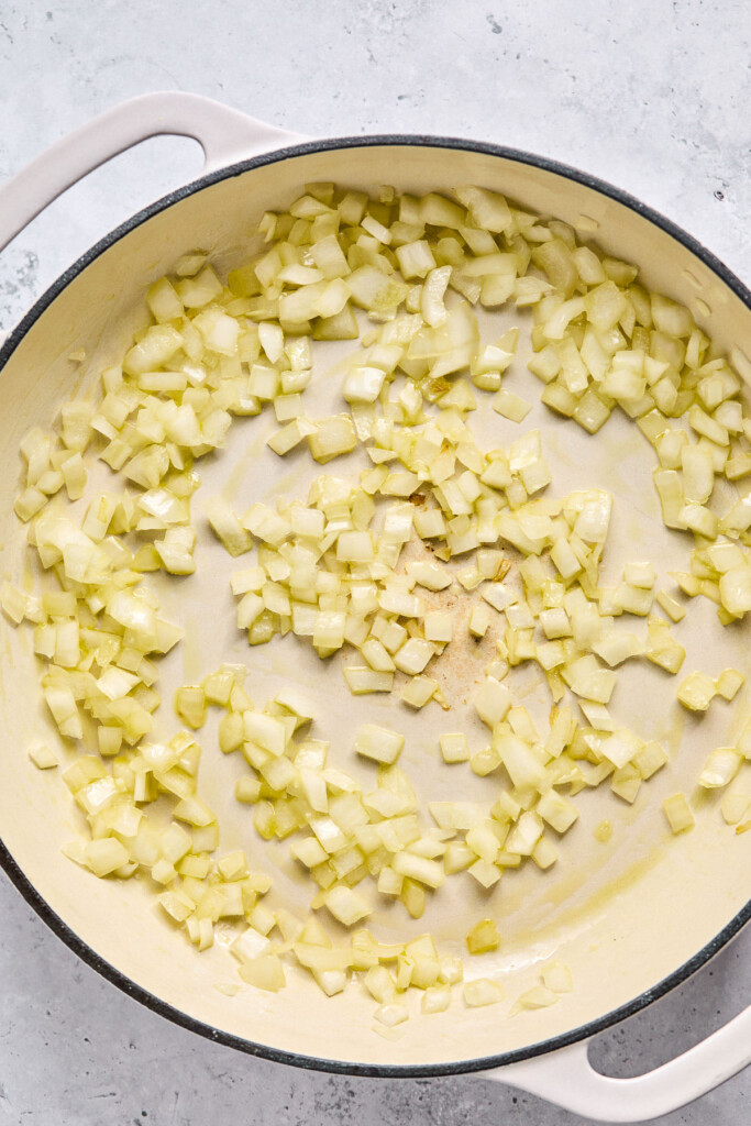 Large enameled pan filled with sautéed onions.
