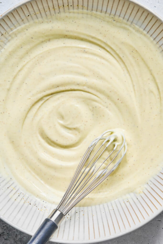 A large bowl with a greek yogurt mixture and a whisk in it.