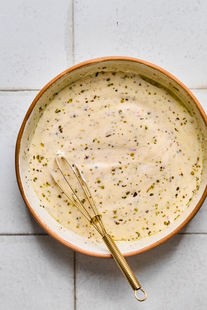 Creamy Italian dressing in a small bowl with a small whisk in it.